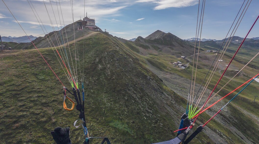 Paragliding Jakobshorn Bergstation | © Davos Klosters Mountains Paragliding Flug in Richtung Jakobshorn Bergstation, die Steuerleinen des Schirmes im Vordergrund. | © Davos Klosters Mountains