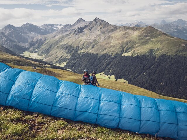 Start Tandemflug Paragliding Jakobshorn | © Davos Klosters Mountains Der Pilot ist gegen den Gleitschirm gerichtet und ist bereit für den Abflug mit dem Gast. | © Davos Klosters Mountains