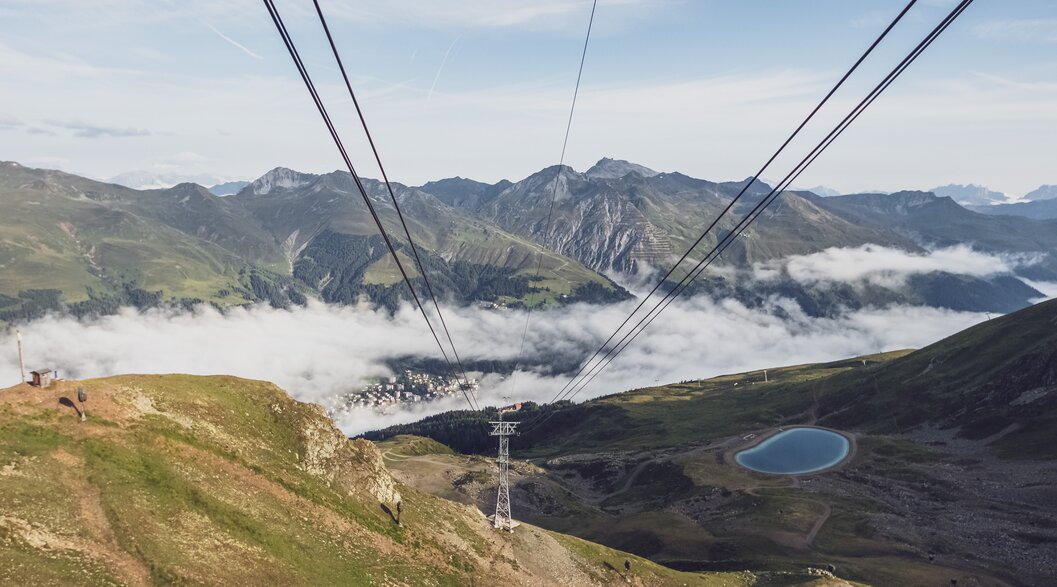 Blick von der Bergstation Jakobshorn ins Tal | © Davos Klosters Mountains Der Blick geht den Seilen der Gondel Jakobshorn entlang ins Tal, wo ein Wolkenmeer liegt. | © Davos Klosters Mountains