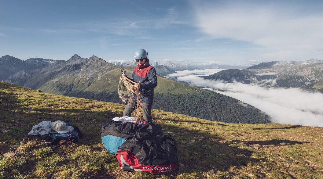 Vorbereitung für den Gleitschirm Tandemflug | © Davos Klosters Mountains Der Pilot packt beim Startplatz Jakobshorn den Gleitschirm aus und bereitet alles für den Flug vor. | © Davos Klosters Mountains