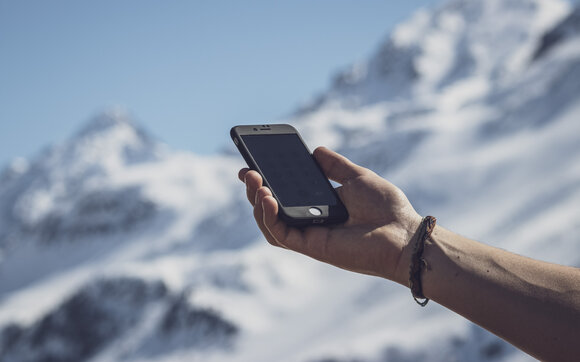  A hand is holding a cell phone. | © Davos Klosters Mountains