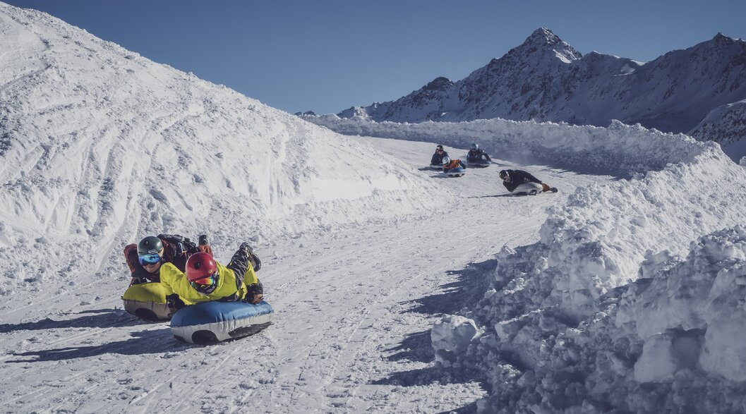 Eine Gruppe Airboarder saust Kopfüber den markierten Weg hinunter. | © Davos Klosters Mountains