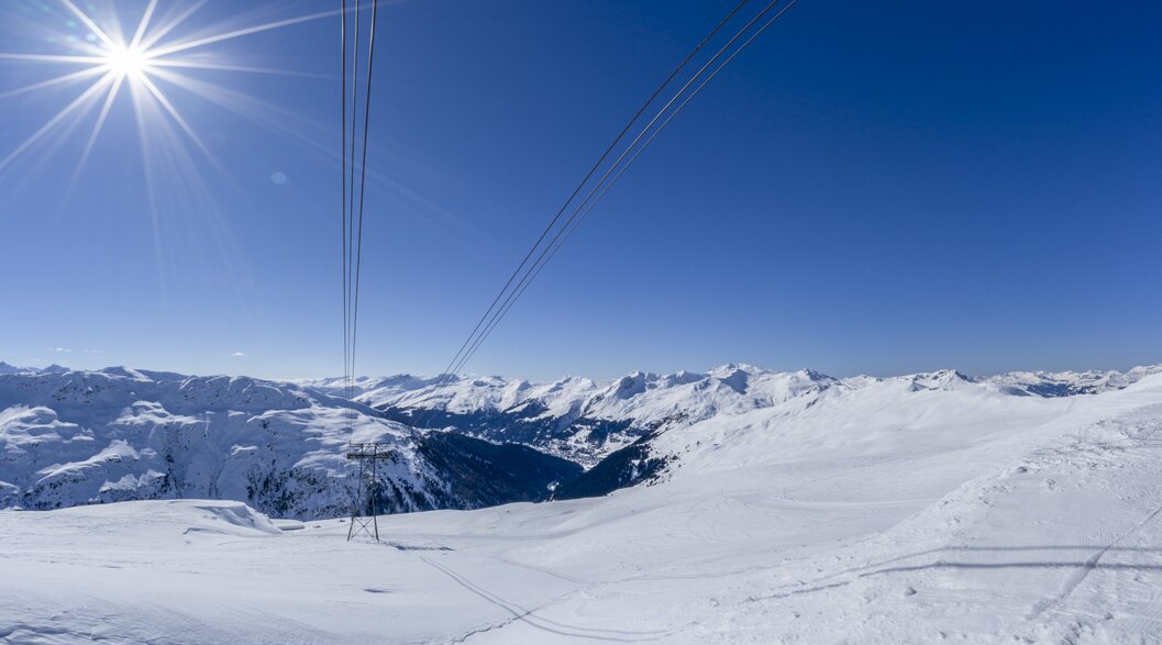 Sonnenstrahlen hüllen das weite Bergpanorama ein, | © Davos Klosters Mountains