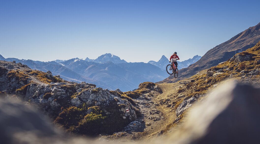 Biker Gotschna Signal Trail | © Davos Klosters Mountians Ein Biker macht einen Sprung auf dem Signaltrail auf Gotschna, das Tinzenhorn im Hintergrund. | © Davos Klosters Mountians