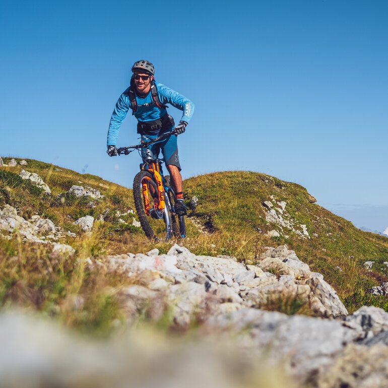 Biker in blauer Kleidung und mit orangem Mountainbike auf Gotschna Parsenn. | © Davos Klosters Mountains