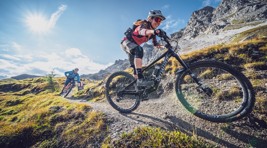 Mountainbike Abfahrt Bikerin | © Davos Klosters Mountains Eine Bikerin geniesst die rasante Abfahrt, ein Biker fährt hinterher. | © Davos Klosters Mountains