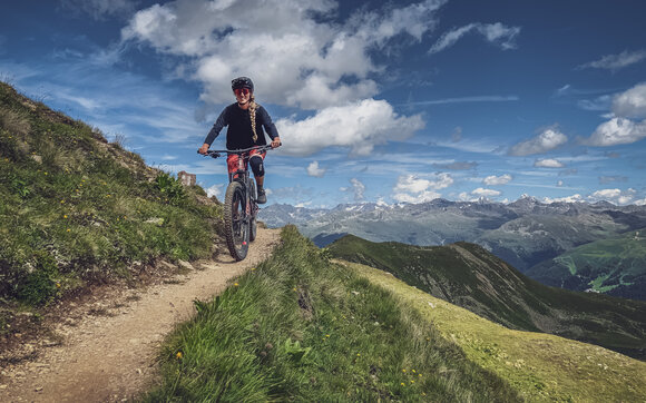 Eine Bikerin ist auf dem Chörbhorntrail unterwegs und geniesst den Tag.  | © Davos Klosters Mountains