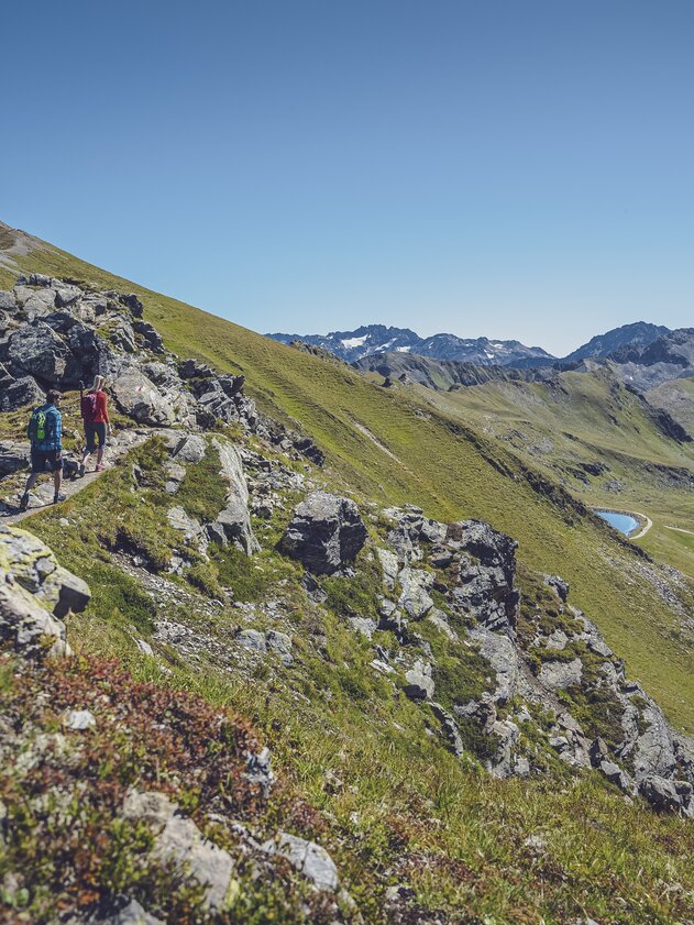 Zwei Wanderer geniessen die Gratwanderung vom Jakobshorn zum Jatzhorn mit dem Stadlersee im Blick.  | © Davos Klosters Mountains