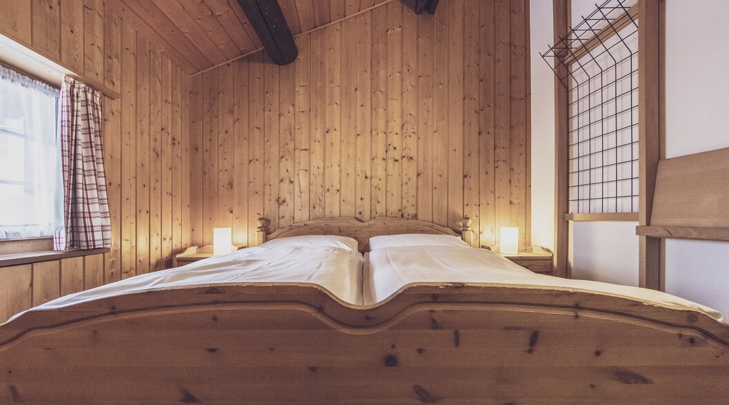Double bed in the bright hotel room with lots of wood | © Davos Klosters Mountains